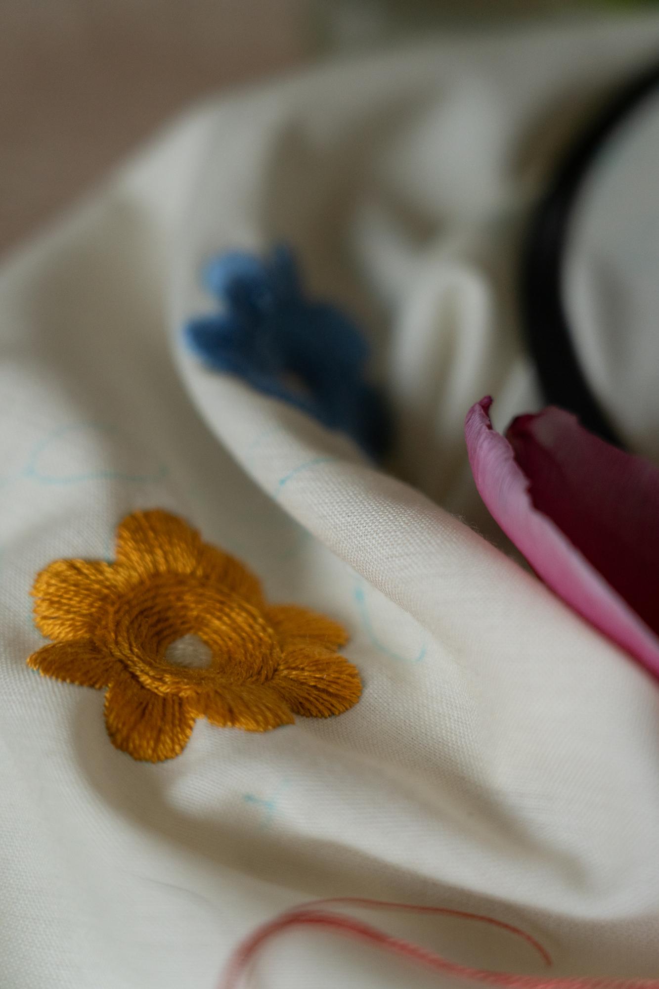 Mano che ricama un fiore su tessuto